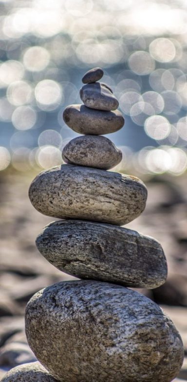 Gestapelte Steine auf einem unscharfen, glitzernden Hintergrund.